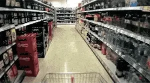 A trolley being pushed down a supermarket drinks aisle