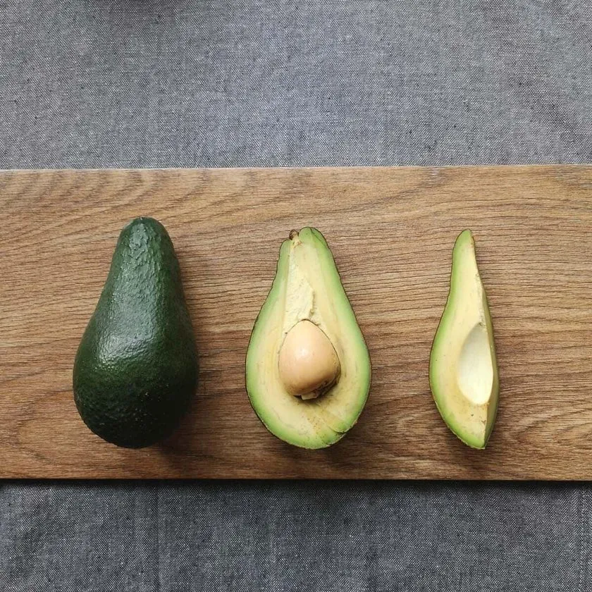 Un avocat entier, un demi-avocat avec noyau et une moitié sans noyau