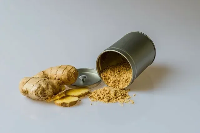 Ginger roots, ginger slices and ground ginger spilling from a metal tin