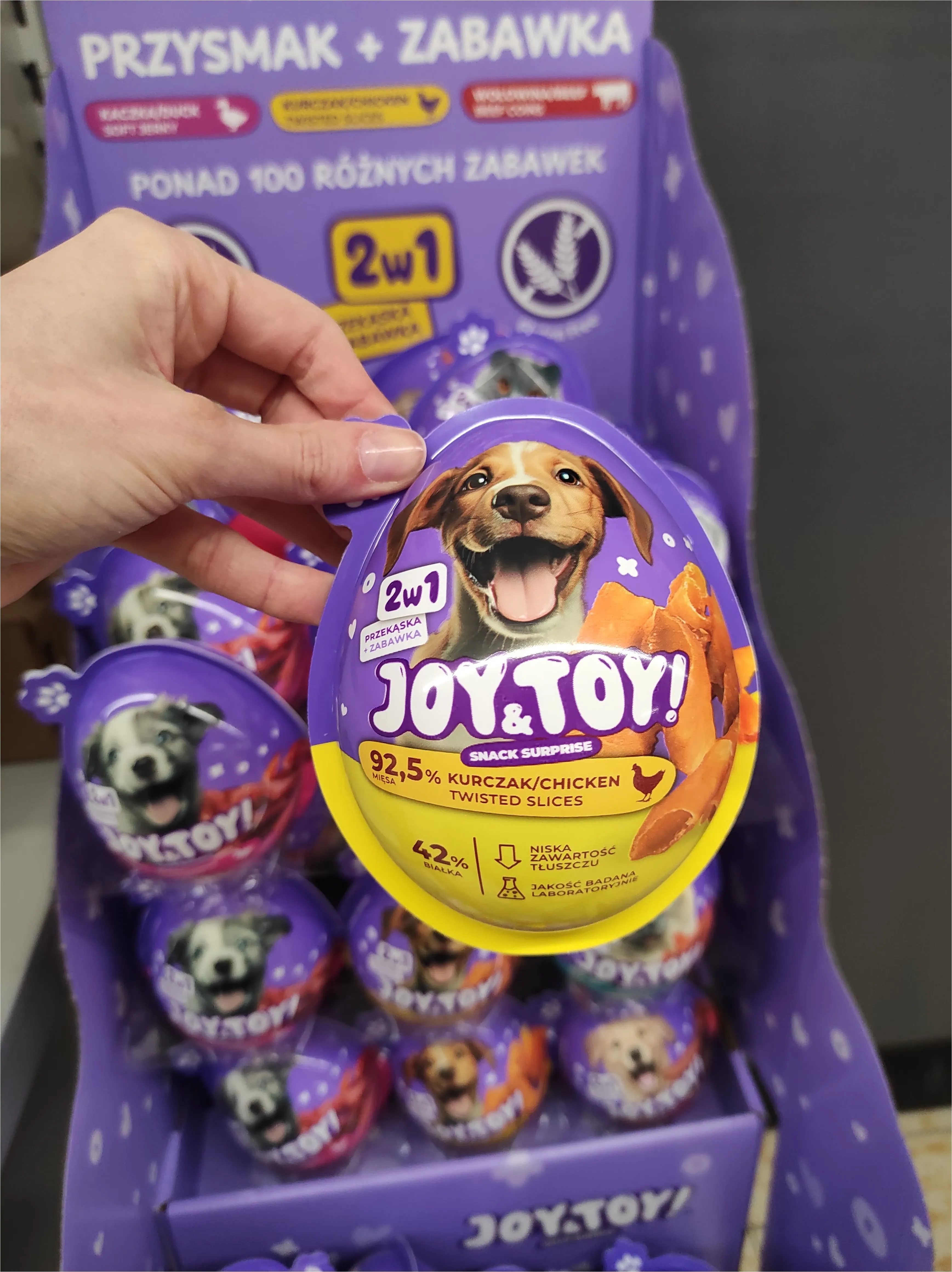 Zdjęcie: dłoń trzyma opakowanie Joy&Toy w kształcie jajka niespodzianki z psem