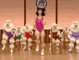 Femme en justaucorps rose entourée de danseurs déguisés en caniches